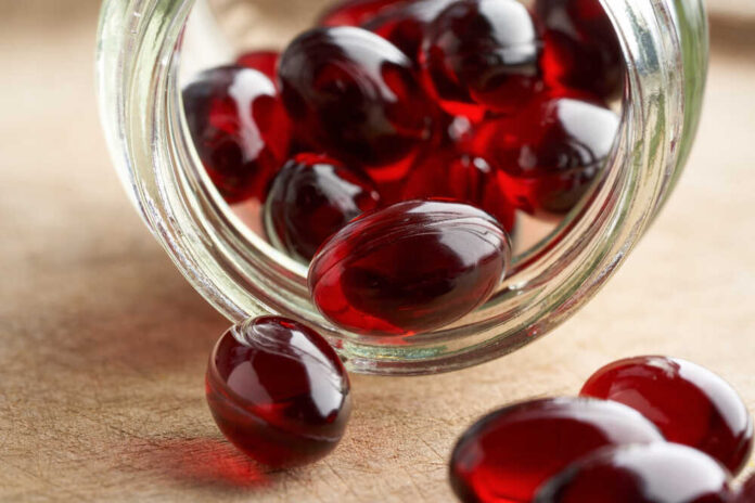Krill oil capsules spilled out of a glass bottle