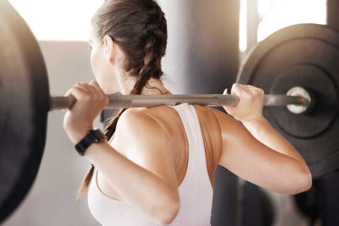Gym, fitness and woman with barbell for training, exercise or workout, progress and body transformation. Sports club, back and power athlete with weightlifting, deadlift and never give up resilience